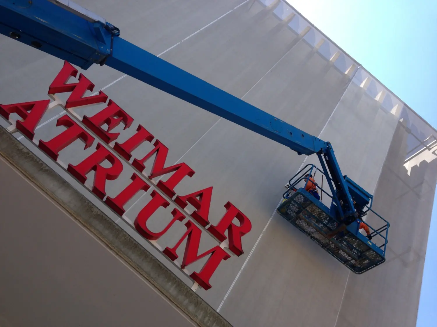 Moderne Raumpflege GmbH Boge - Gebäudereinigung - Arbeiter nutzen eine mobile Hubarbeitsbühne (MEWP), um den hohen Außenbereich eines Gebäudes zu erreichen